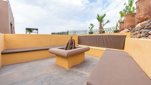 A rooftop terrace with a fire pit, seating, and potted plants. - Life Resort (Marrakech)