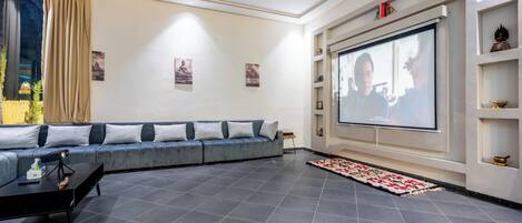 A modern living room with a grey sofa, a flat-screen TV mounted on the wall, and a small coffee table.