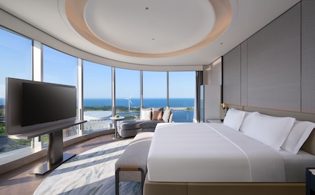 A modern hotel room with a large bed, a flat-screen TV, and a panoramic ocean view.. Crowne Plaza Weihai Binhai