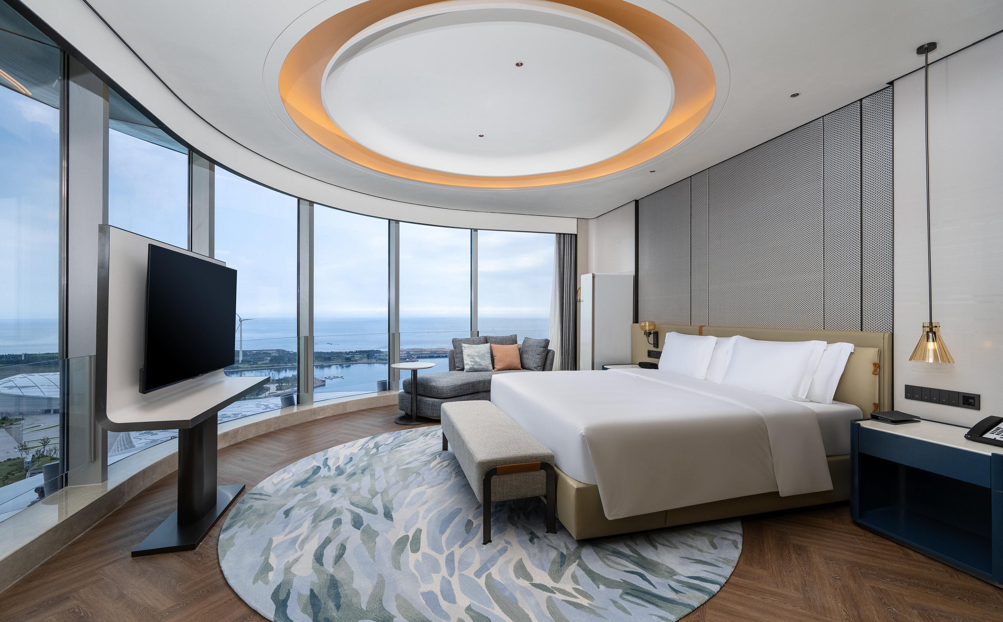 Un hotel moderno con una cama grande, televisión de pantalla plana, escritorio y vistas al océano.