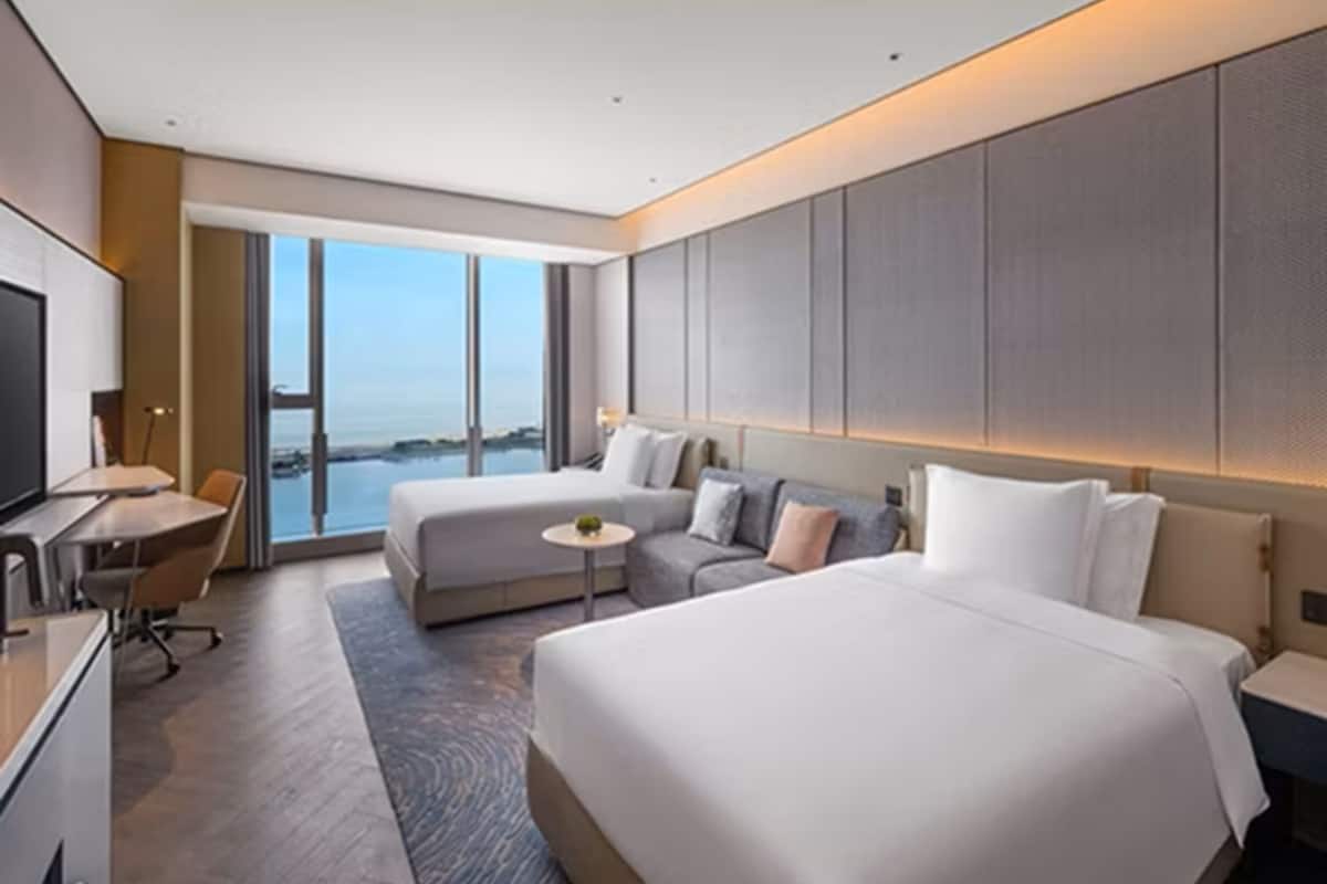 Une chambre d’hôtel moderne avec un grand lit, un canapé, une petite table, un bureau et un téléviseur.