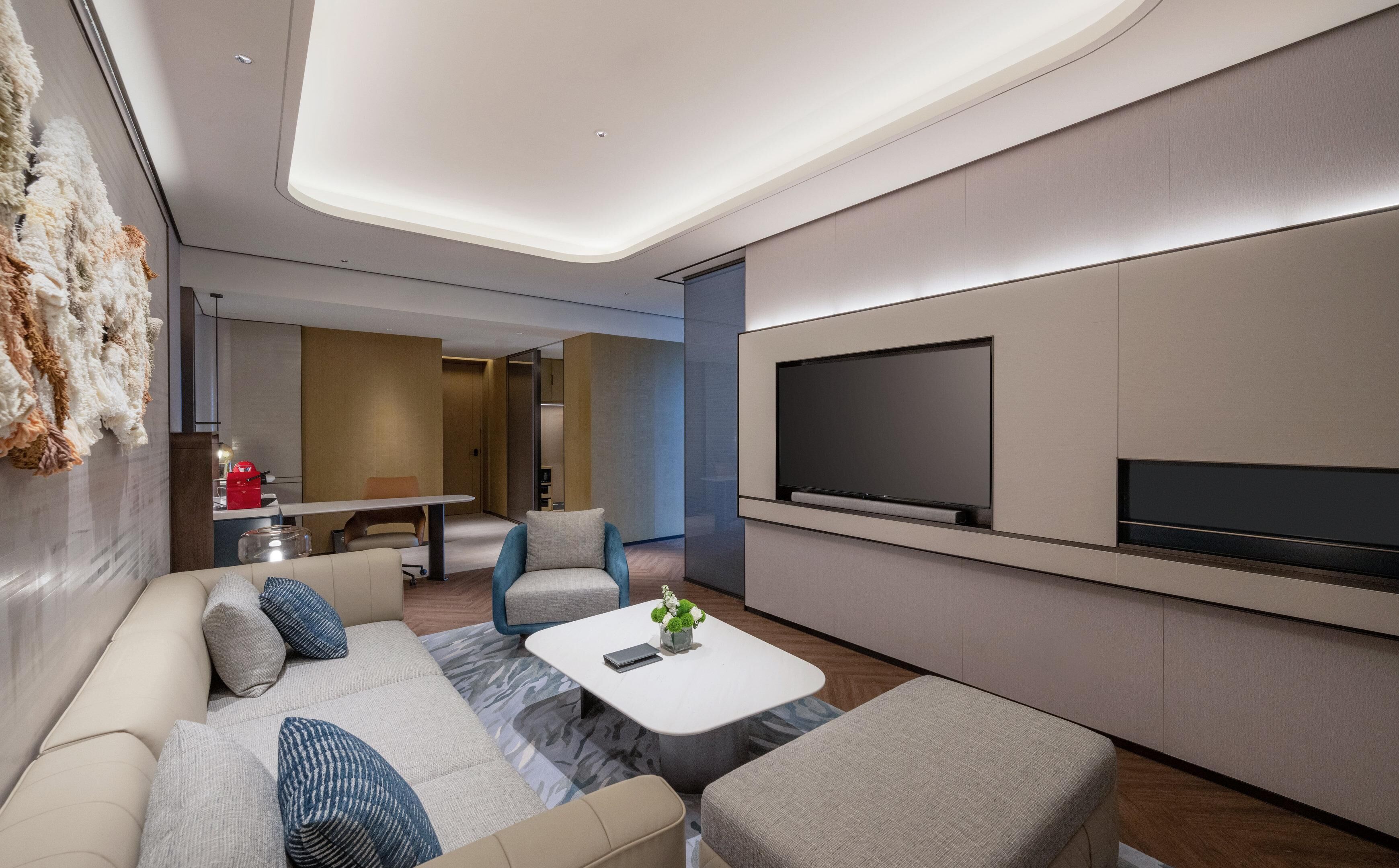 Una sala de estar moderna con un sofá, una mesa de centro y un televisor de pantalla plana montado en la pared.