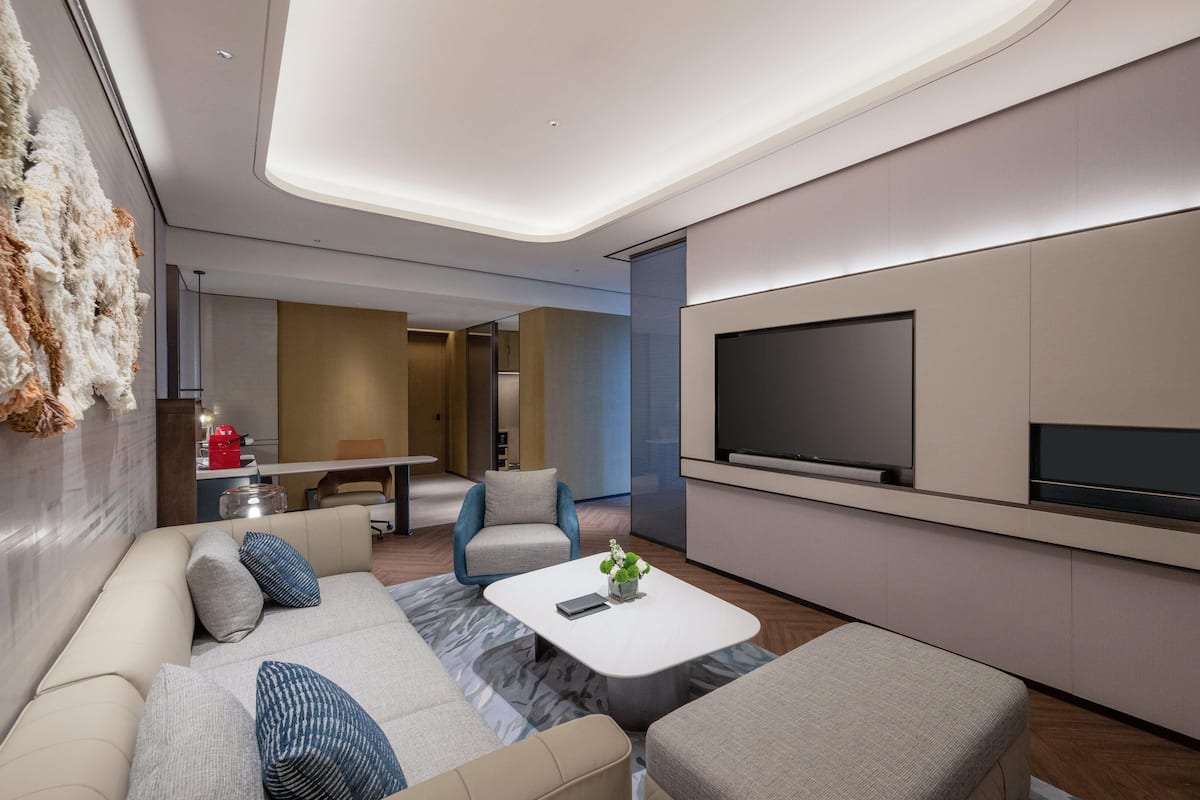 Un salon moderne avec un canapé, une table basse et un téléviseur à écran plat fixé au mur.