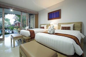 A hotel room with two beds, a bench, a view of a pool, and a wooden headboard. - Batu Empug Hotel (Ubud)