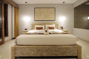 A neatly made bed with a heart-shaped decoration, a wooden headboard, and a wall-mounted artwork. - Batu Empug Hotel (Ubud)