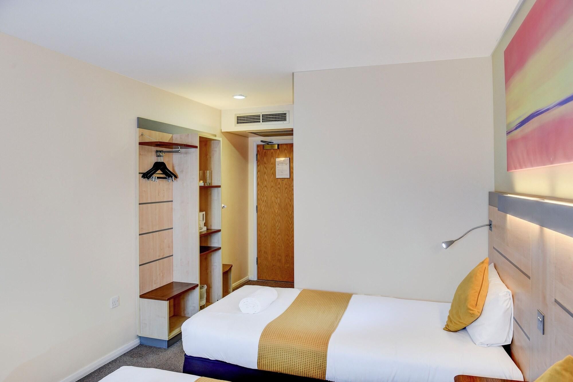 A hotel room with a bed, a wardrobe, and a bathroom.