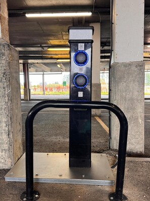 A parking garage entrance with a metal barrier and a QR code on a vertical sign. - Belvilla Aberdeen Bridge of Don Sea View (Aberdeen)
