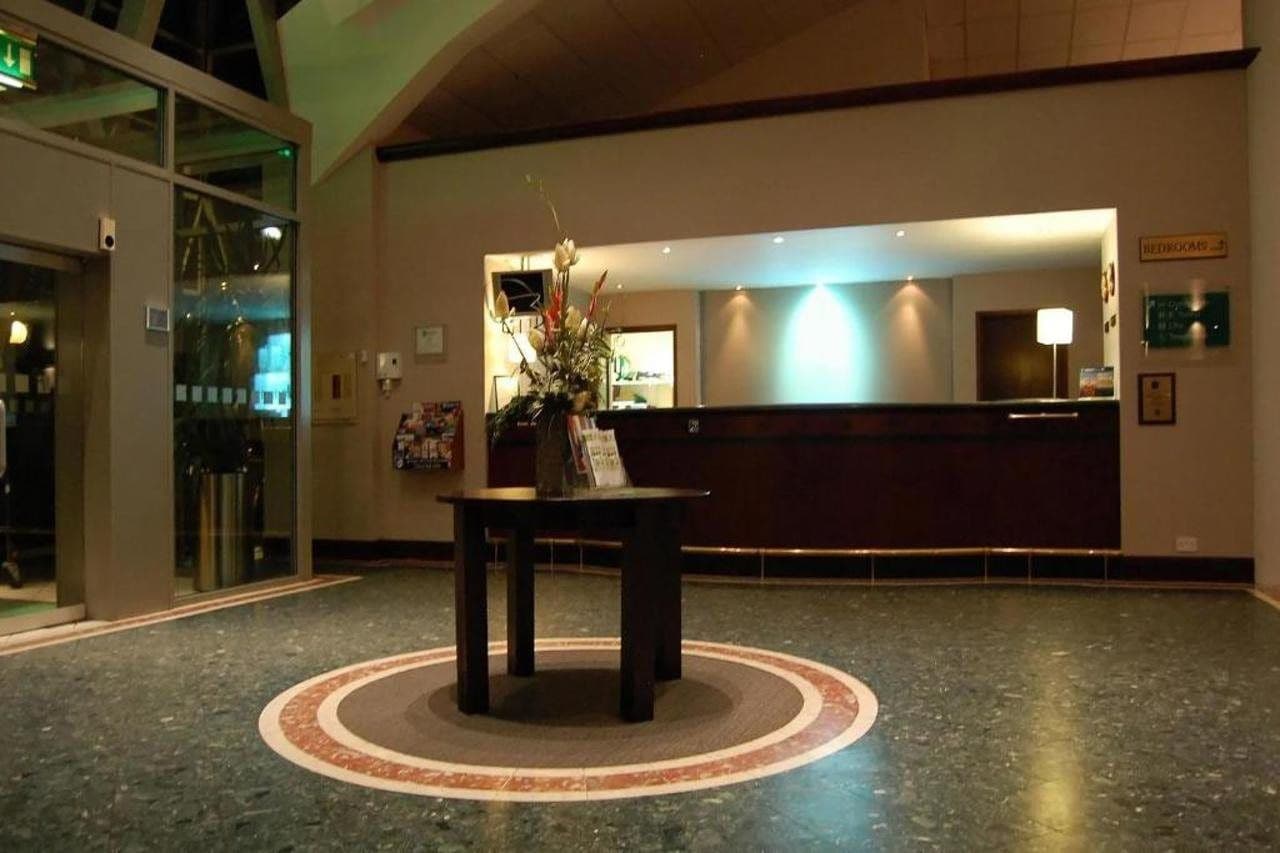Un vestíbulo con mostrador de recepción, un diseño de alfombra circular y una zona de recepción con una planta.