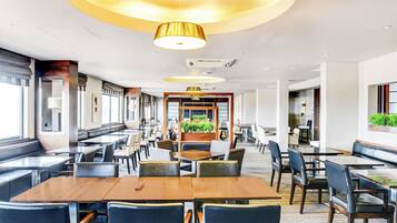 A spacious restaurant with high ceilings, modern lighting, and a mix of seating arrangements including booths and tables.