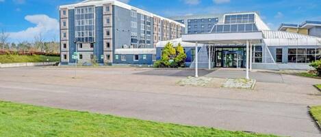 Un edificio moderno con ingresso coperto, parcheggio e area verde.