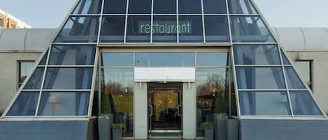A modern restaurant with a glass facade and a triangular entrance.