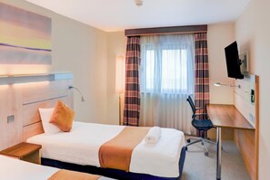 A hotel room with a bed, a desk, a chair, a TV, and a window with curtains. - Belvilla Aberdeen Bridge of Don Sea View (Aberdeen)