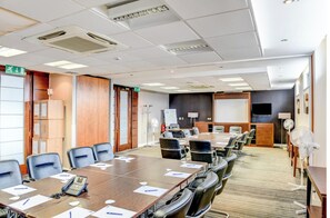 A conference room with a long table, chairs, a whiteboard, a projector screen, and a whiteboard stand.