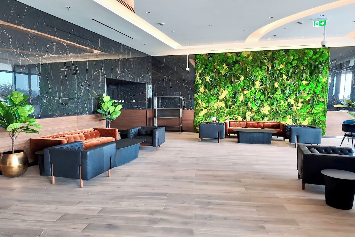 A modern lobby with a marble wall, green wall decor, and contemporary seating arrangements.