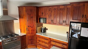 Una cocina moderna con armarios de madera, electrodomésticos de acero inoxidable y encimera blanca.