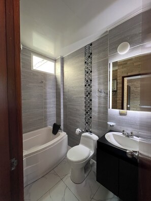 Un bagno moderno con vasca, servizi igienici e lavandino.