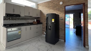 A modern kitchen with a built-in oven, a black refrigerator, and a tiled floor. - The Cayetano House (Cali)