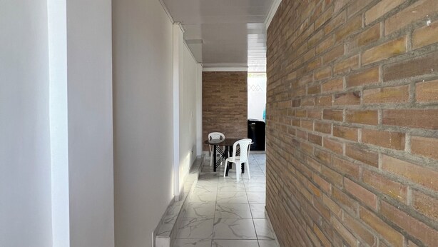 A corridor with a marble floor, white walls, and a brick wall on one side. - The Cayetano House (Cali)