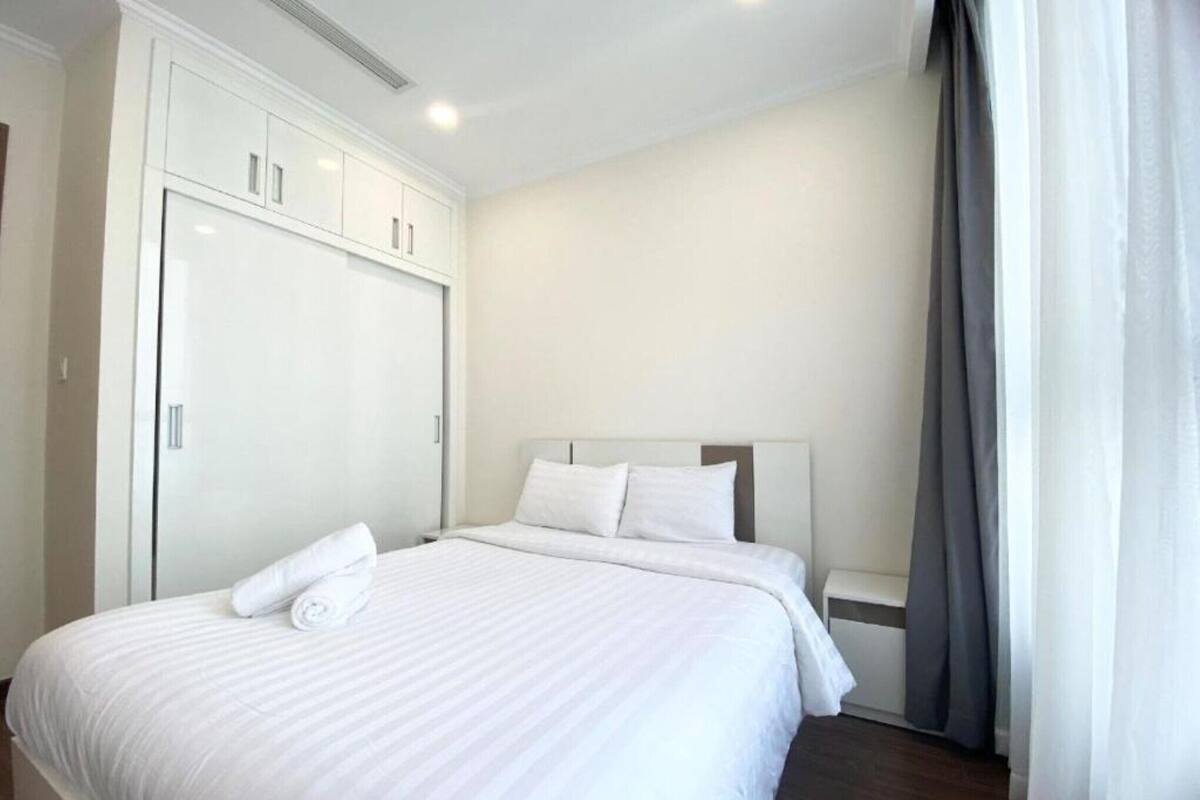 Una habitación de hotel con una cama grande, un armario y una ventana con cortinas.