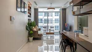 A modern kitchen with a dining area, large windows, and a view of the city. - Vinhomes Central Park AnAn Apartment (Ho Chi Minh City)