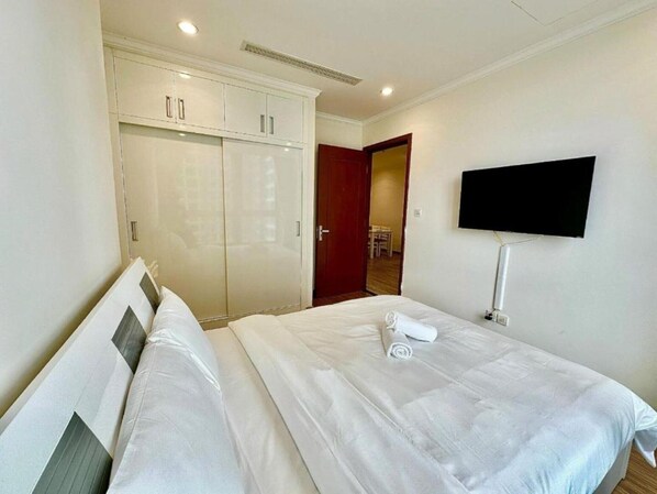 Une chambre d’hôtel comprenant un lit, une armoire, un téléviseur fixé au mur et une porte donnant accès à une salle de bain.