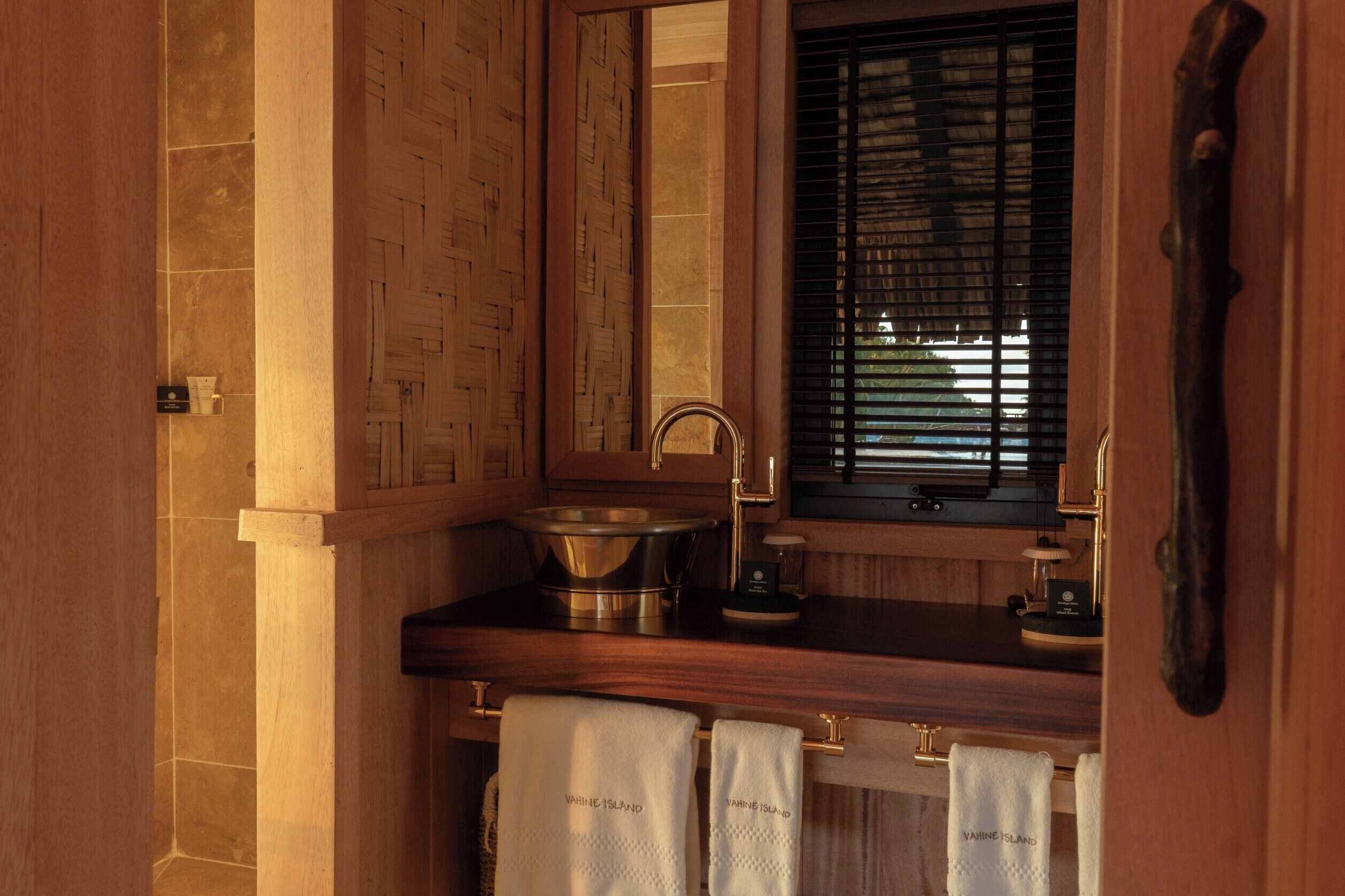 A bathroom with a wooden vanity, a sink, a mirror, and a window with blinds.