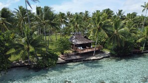 A tropical resort with a wooden structure surrounded by palm trees and clear turquoise water. - Vahine Private Island (Taha'a)