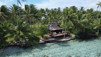 Un resort tropical con estructura de madera, rodeado de palmeras y agua turquesa cristalina.