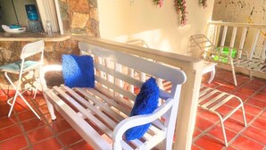 Un banc blanc avec des coussins bleus, un mur en pierre et un sol carrelé.