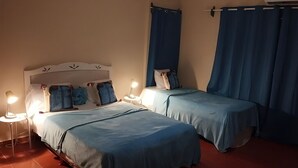 Une chambre à coucher avec deux lits, chacun doté d’une tête de lit, de lampes de chevet et de linge de lit bleu.