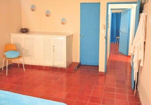 Une pièce comprenant un lit, une armoire, une chaise et une porte donnant sur une autre pièce.