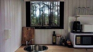 Una cocina con ventana, un lavabo, un microondas y una cafetera.