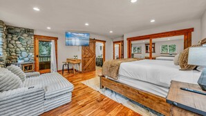 A spacious bedroom with a large bed, a wooden headboard, and a stone wall. - Kings Beach Retreat | Hot Tub & Game Loft (Kings Beach)