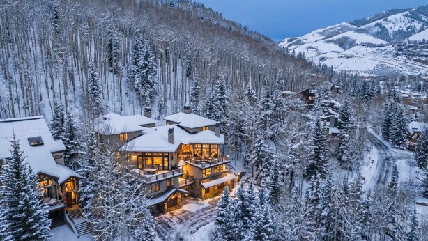 Eine mehrstöckige Lodge mit einem zentralen Innenhof, umgeben von schneebedeckten Bäumen und Bergen.