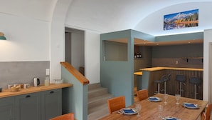 A modern kitchen with grey cabinets, a wooden countertop, and a dining area with a wooden table set for four.