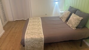 A bedroom with a bed, two pillows, a window with curtains, and a green wall.