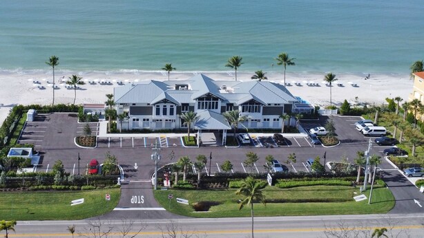 A hotel with a parking lot, a stop sign, and a beach in the background.