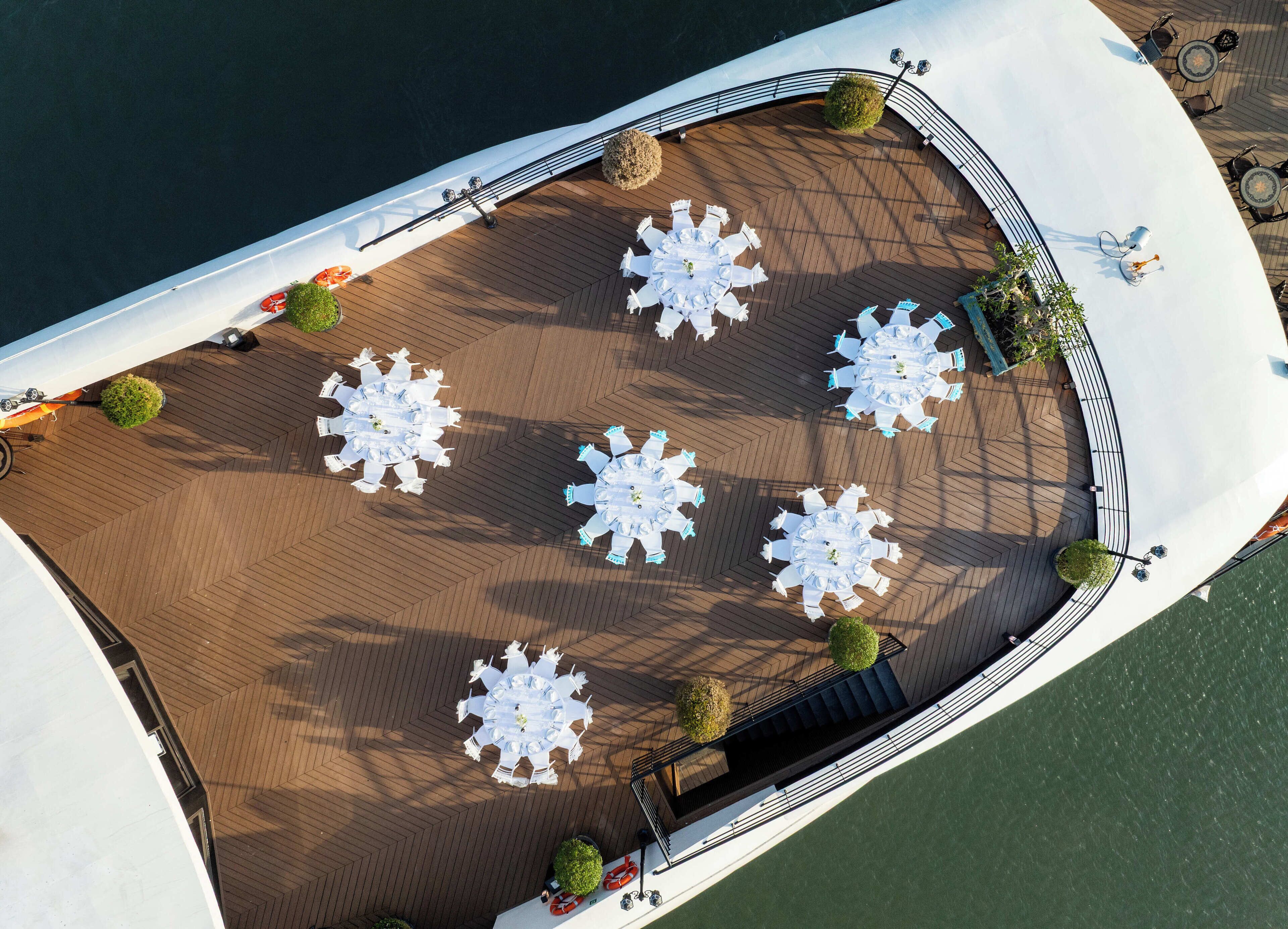 An aerial view of a cruise ship deck with multiple round tables and chairs, arranged in a circular pattern.