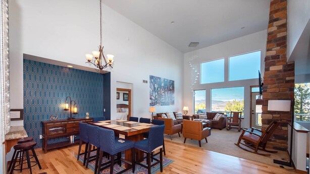 A spacious living room with a dining area, large windows, and a stone fireplace. - Red Barn of Granby Ranch - spacious luxury, pet friendly and hot tub (Granby)