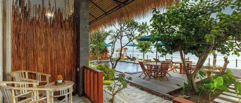 Une terrasse en bois avec des meubles d’extérieur, une piscine et une vue sur la mer.