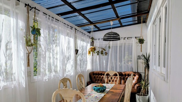 A dining area with a wooden table, white chairs, and a brown leather couch. - The Wildflower Cottage - 5 minutes to the heart of the Blue Mountains (Katoomba)