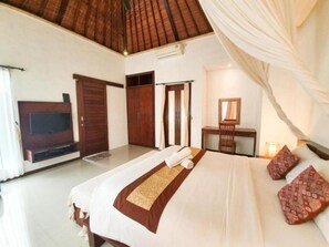 A hotel room with a large bed, a television, a wardrobe, and a mirror.