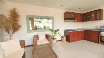 A modern living room with a sofa, a coffee table, and a dining area with wooden cabinets and a kitchen island.
