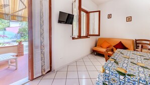 A room with a sofa, a TV mounted on the wall, and a tiled floor. - Casa dei Fiori - Goelba (Portoferraio)