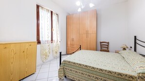 A bedroom with a bed, wooden wardrobe, and a chair. - Casa dei Fiori - Goelba (Portoferraio)