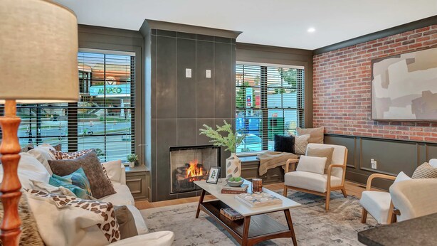 Una sala de estar moderna con chimenea, asientos cómodos y vistas al exterior a través de amplios ventanales.