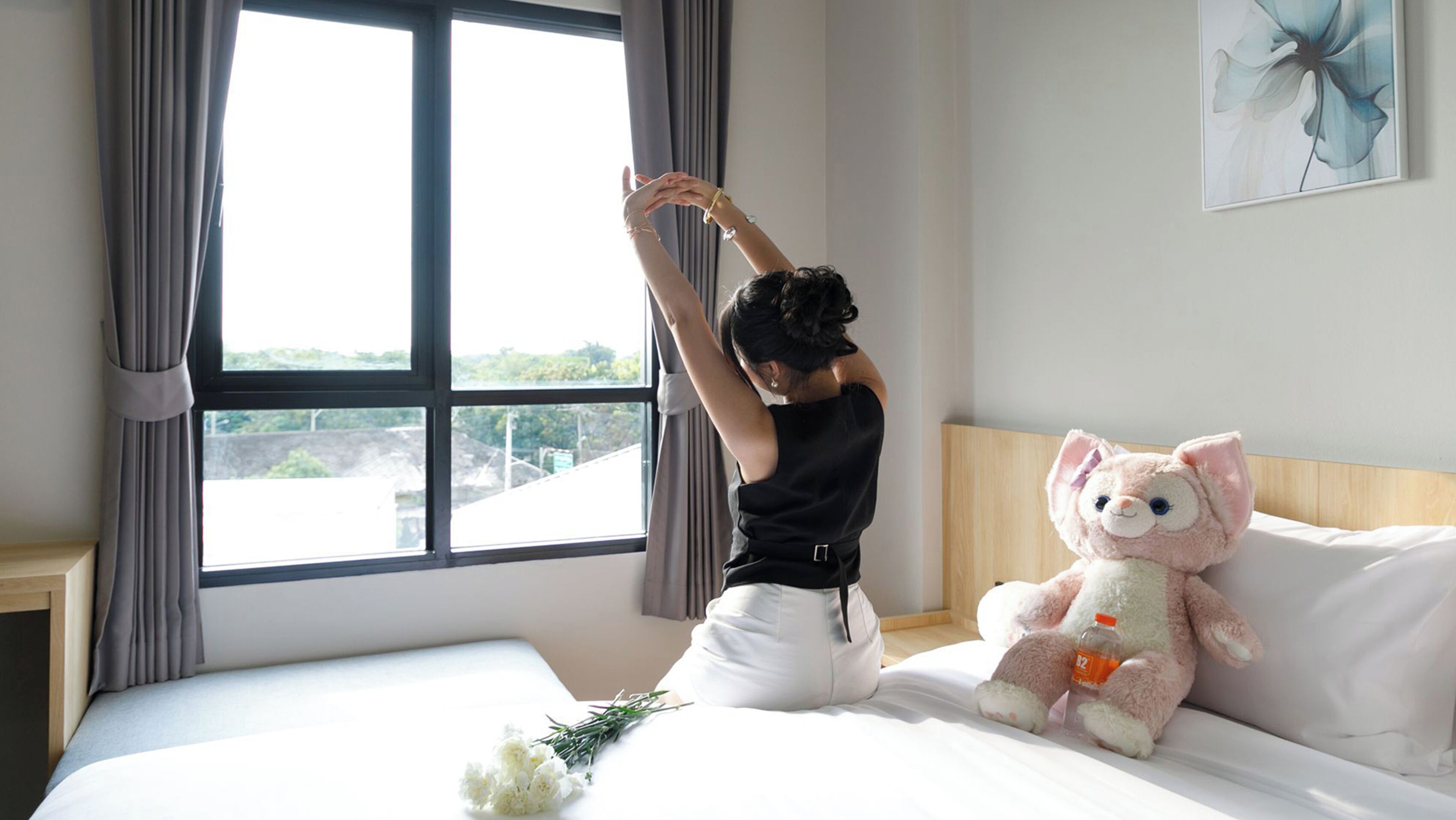 Una habitación con una cama, un ventanal grande y un peluche.
