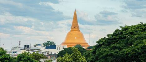 Un grand stupa doré, entouré d’une végétation luxuriante et de bâtiments.