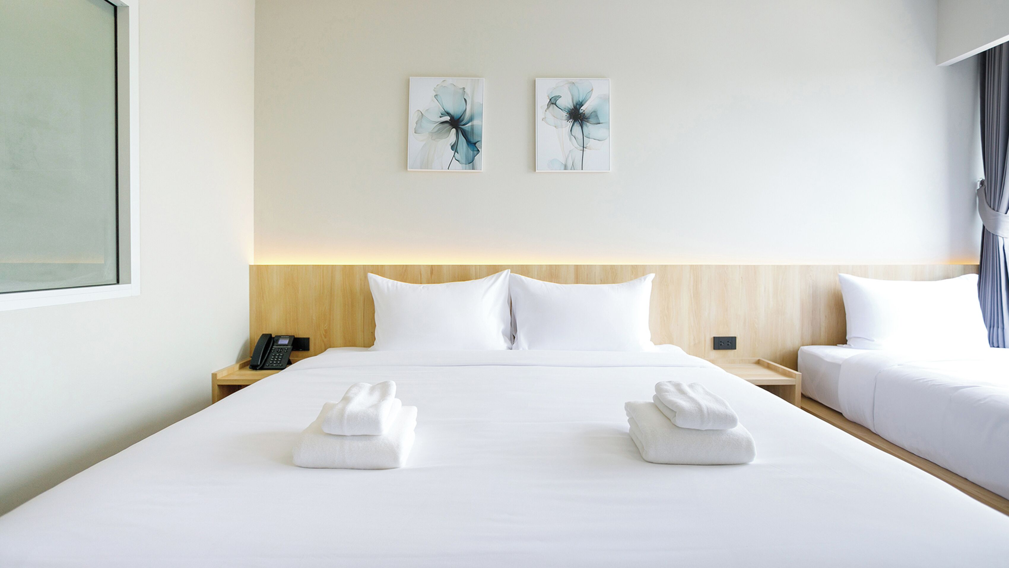 Habitación de hotel con una cama grande, dos mesitas de noche, un teléfono y obras de arte en la pared.