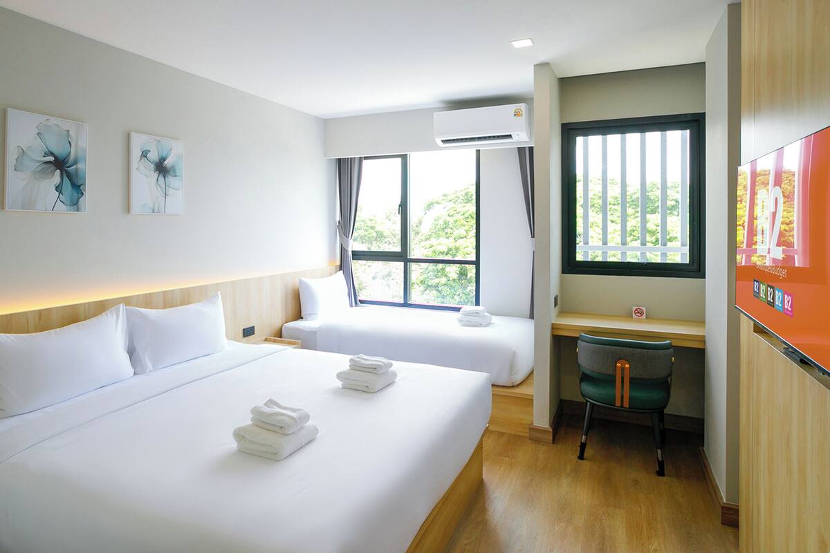 Une chambre d’hôtel avec un grand lit, un bureau, une chaise et un téléviseur.